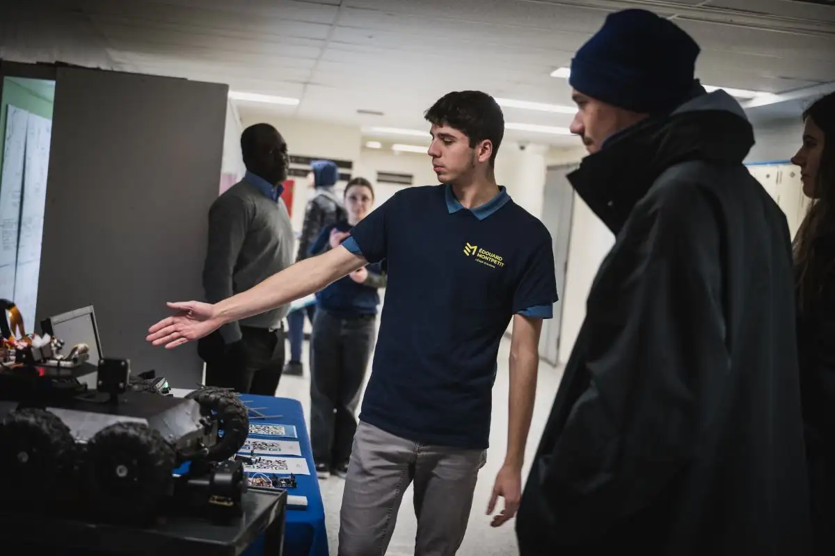 Personne étudiante du programme techniques du génie électronique qui présente des créations à des visiteurs