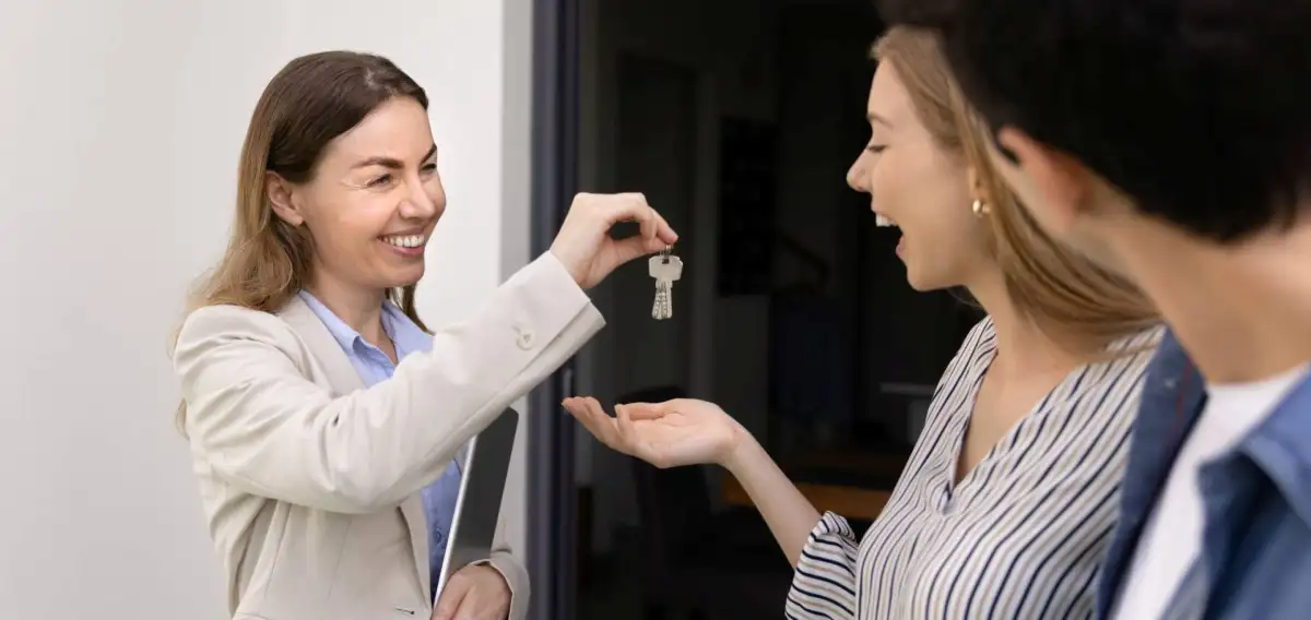 Un couple qui reçoit une clé pour une maison grâce à une courtière.