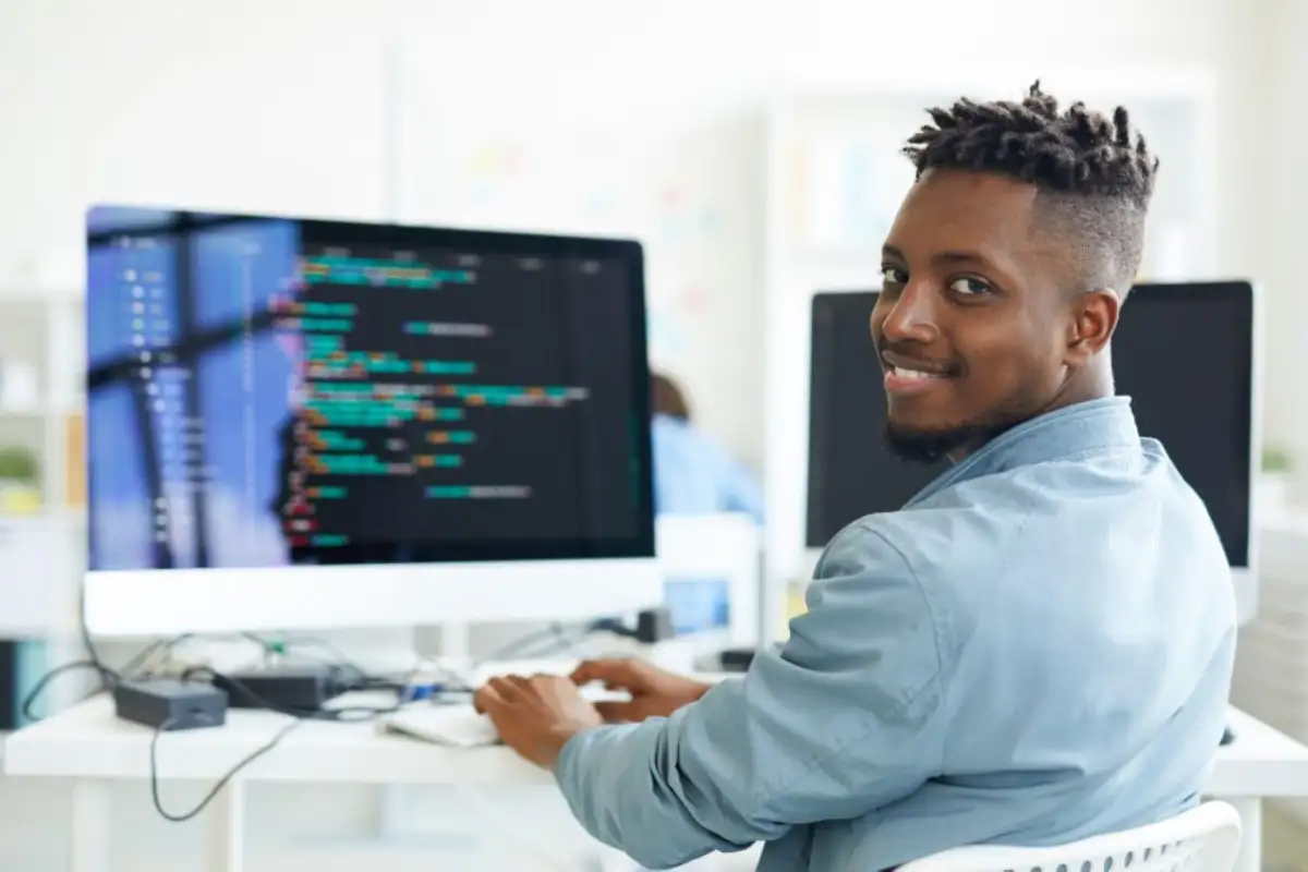 Un homme qui regarde l'objectif devant un ordinateur