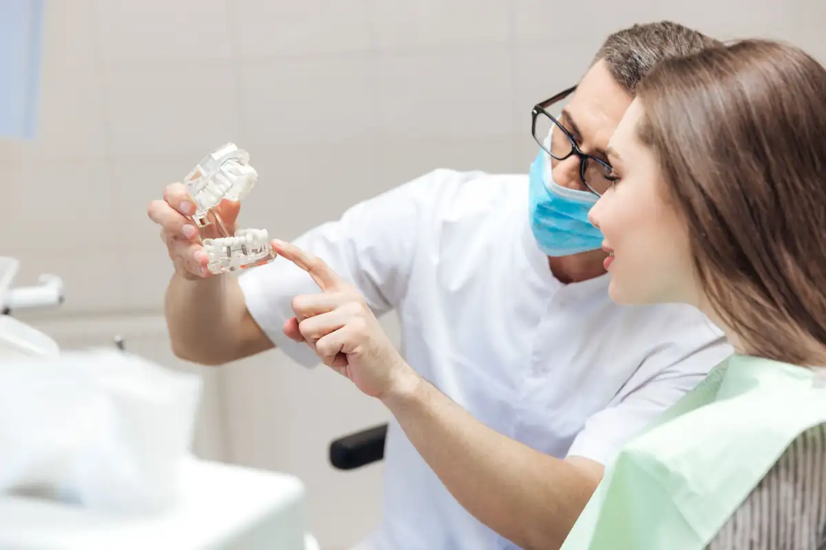 Un denturologue qui montre un dentier à une patiente