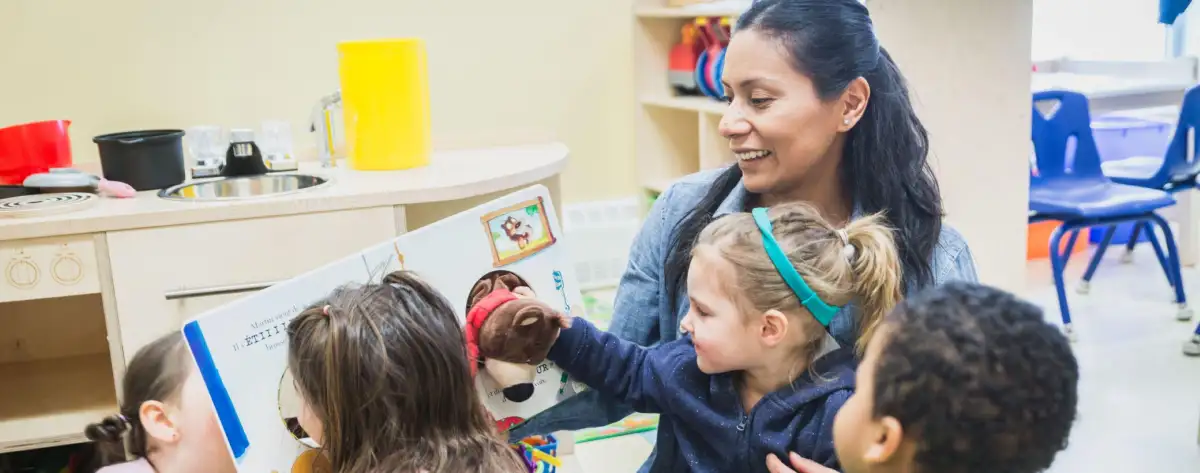 Un éducatrice qui montre un livre à plusieurs enfants