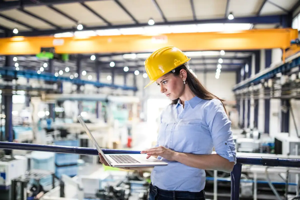 Femme tenant un ordinateur portable dans une usine