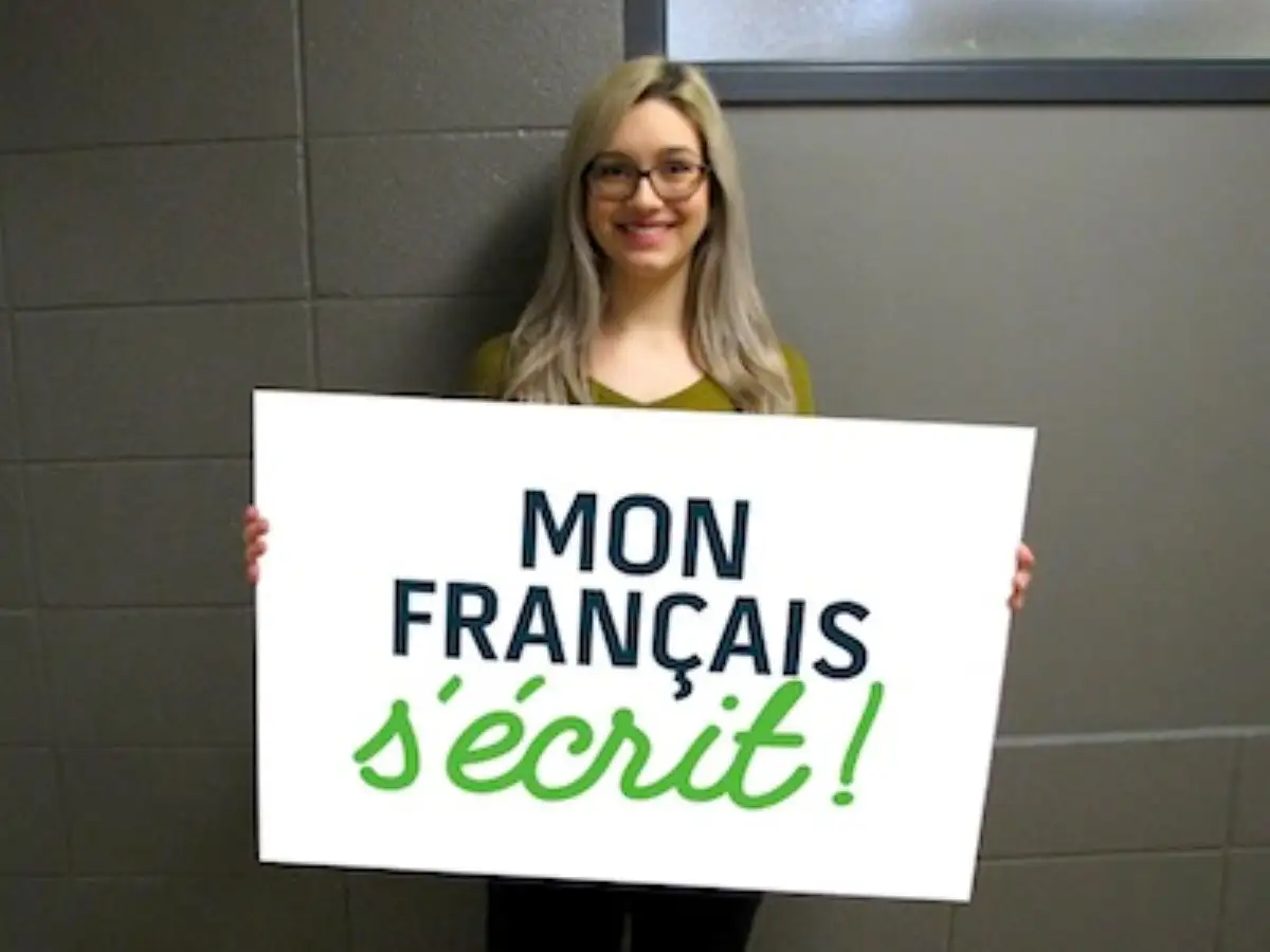 Étudiante qui tient un écriteau "Mon français s'écrit"