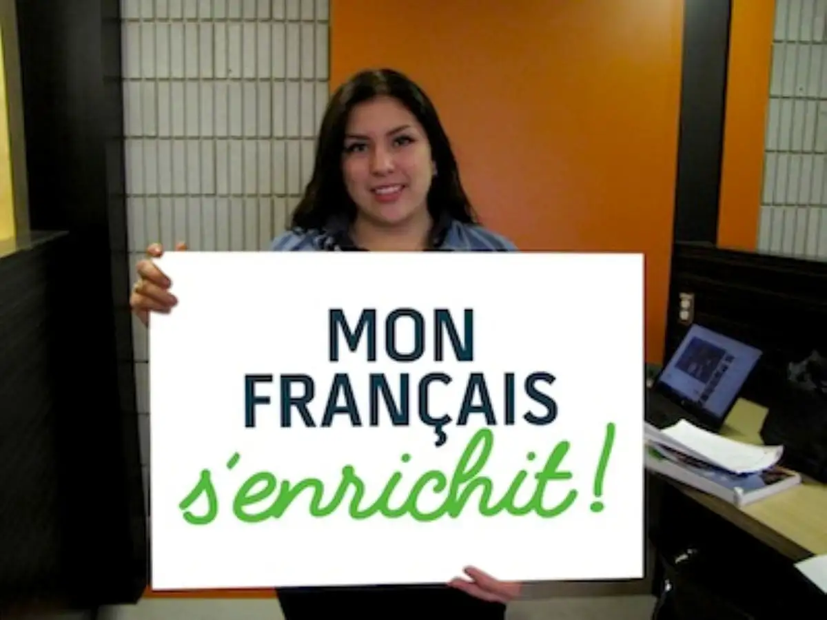 Étudiante qui tient une pancarte "Mon français s'enrichit"