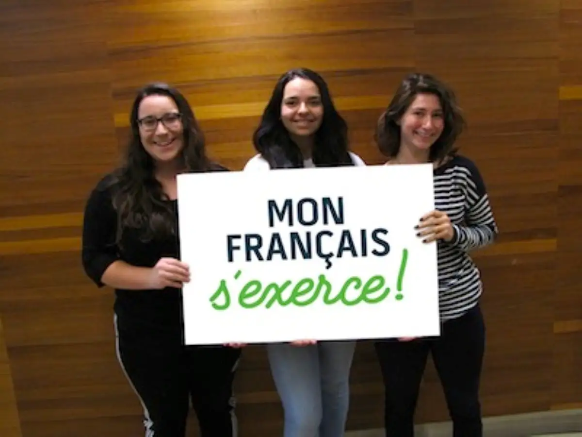 Étudiantes qui portent une pancarte "Mon français s'exerce"
