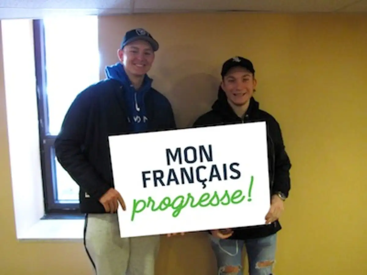 Étudiants qui portent une pancarte "Mon français progresse"