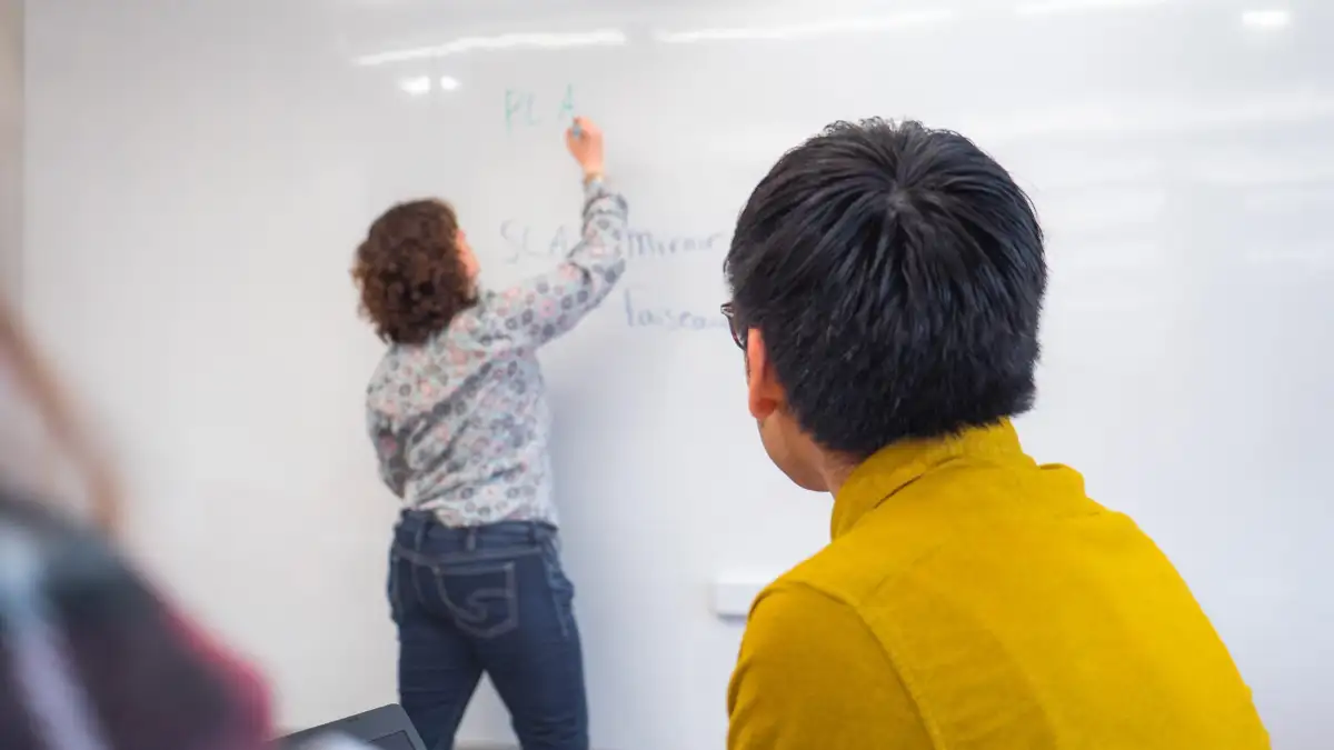 Personne qui écrit sur un tableau blanc