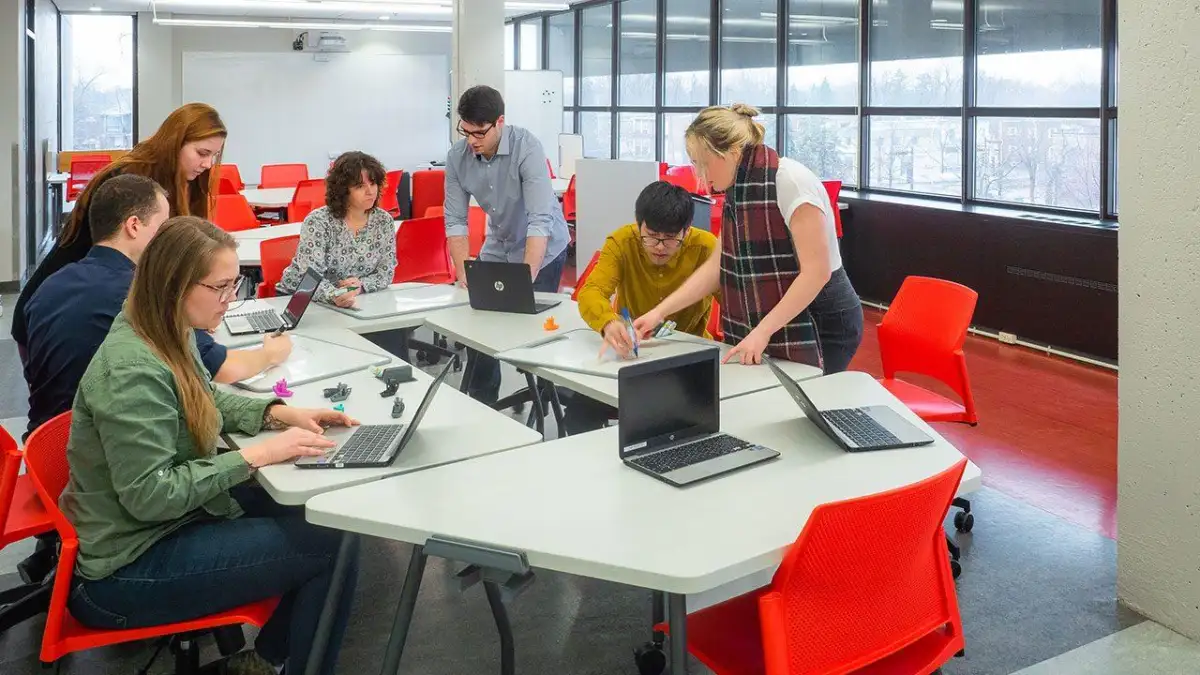 Groupe de personnes qui collabore autour d'une table avec des ordinateurs et impressions 3D