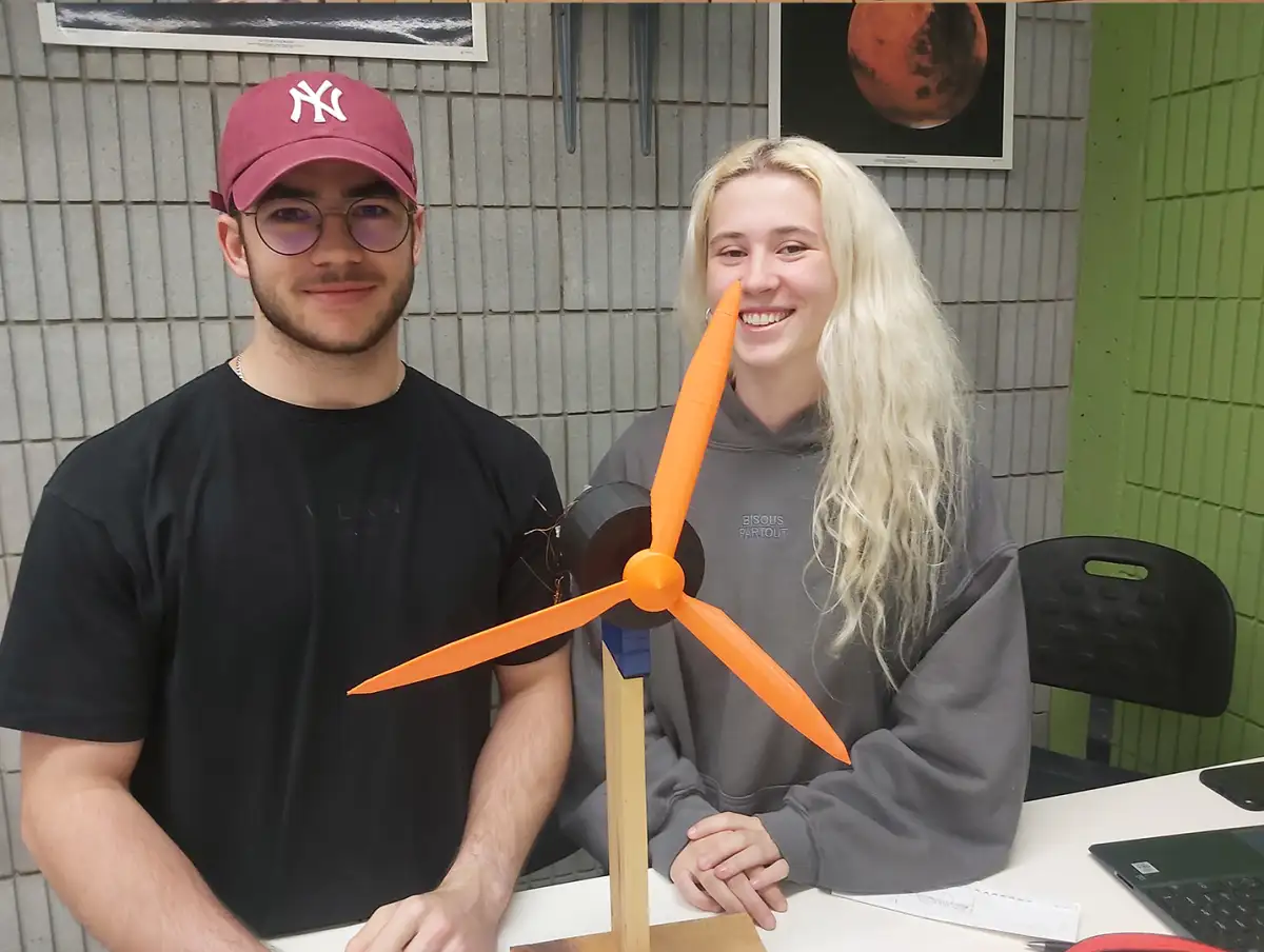 2 personnes étudiantes face caméra avec leur modèle d'éolienne en 3D