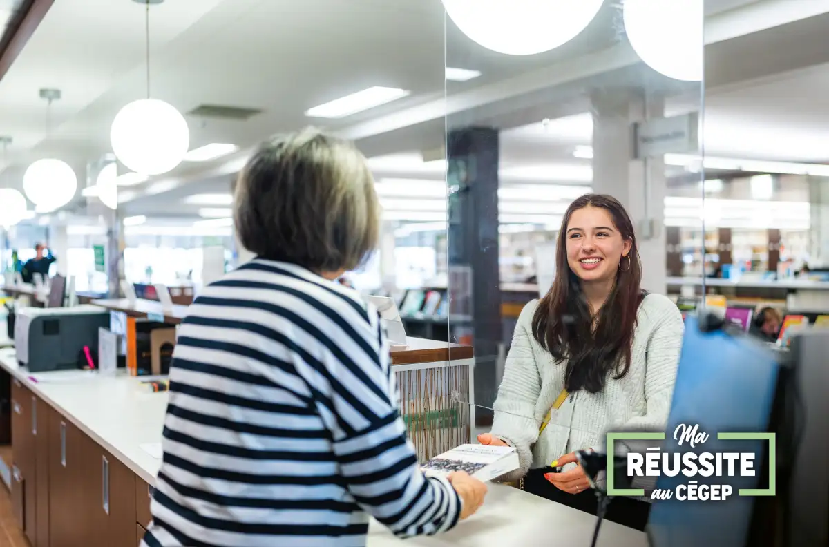 Personne étudiante souriante qui reçoit les services d'une personne à la bibliothèque