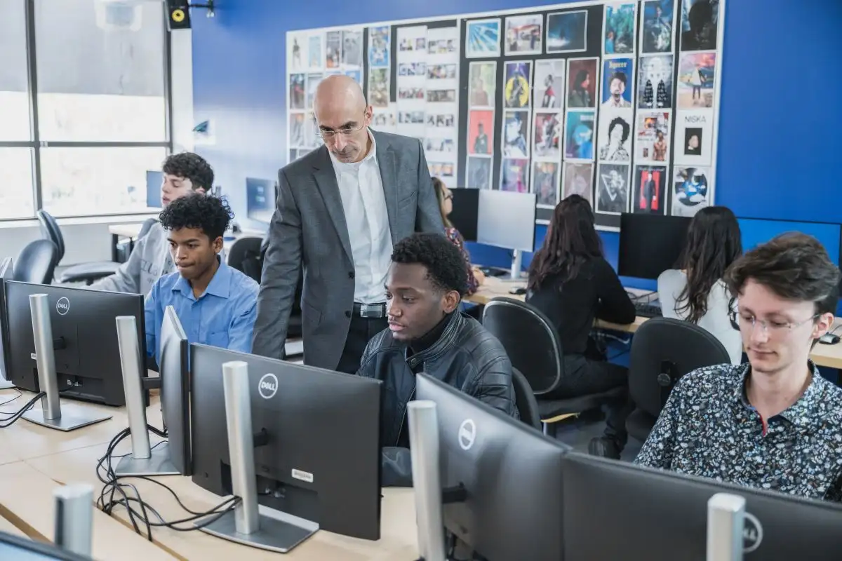 Enseignant qui fait le tour des élèves assis à leur ordinateur
