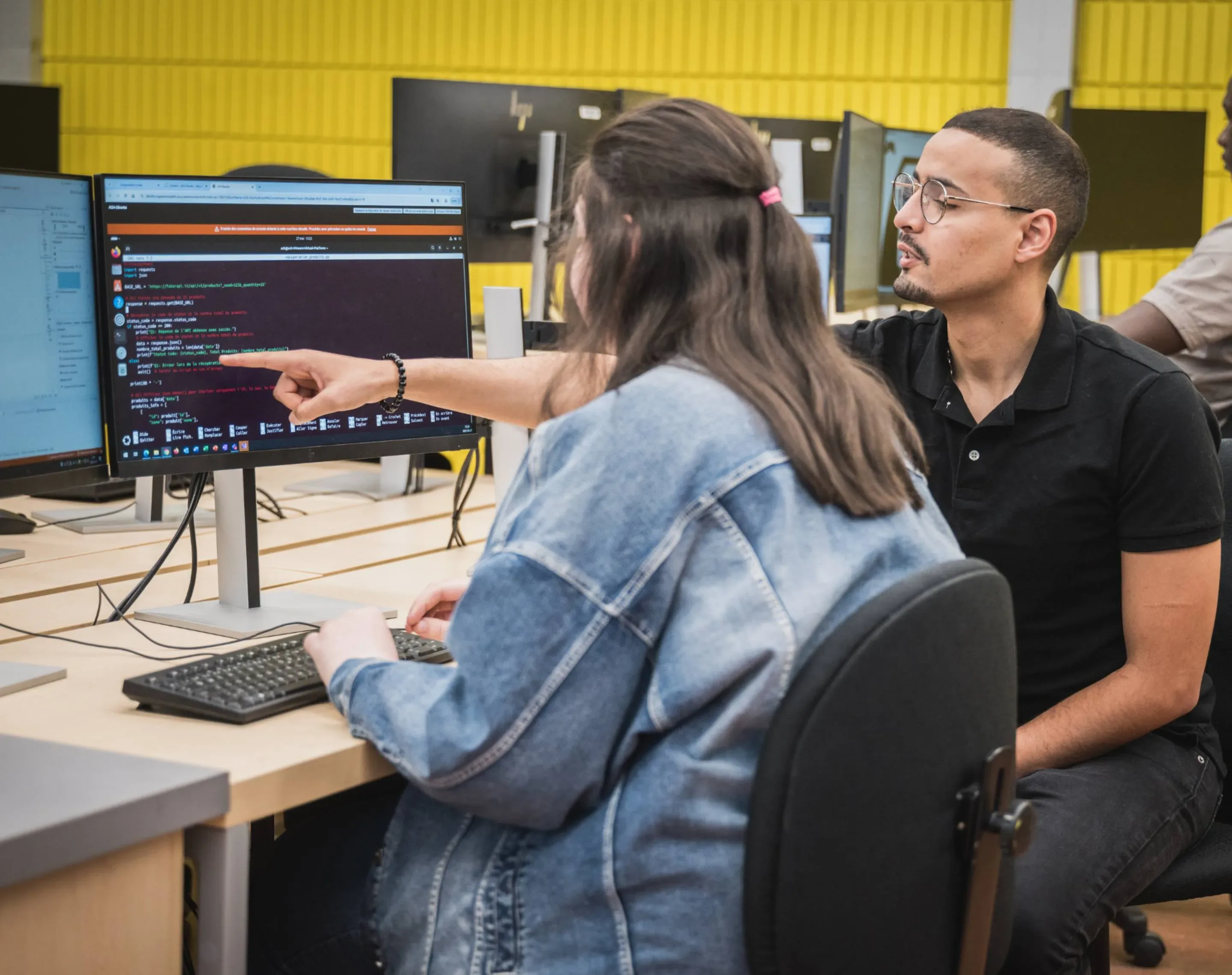 Enseignant qui donne des explications à une étudiante en face d'un ordinateur