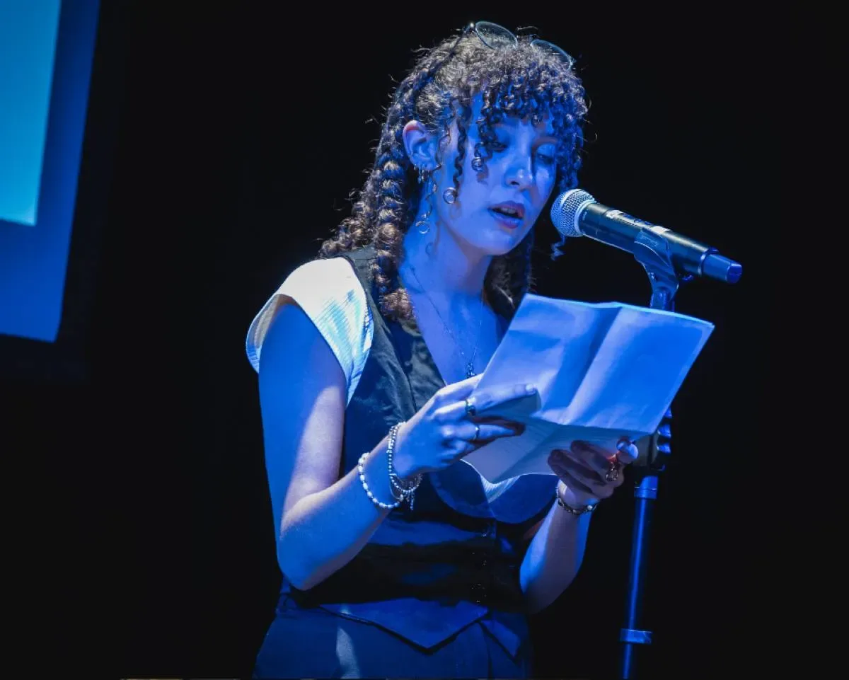 Étudiante qui lit un texte devant un micro sur scène