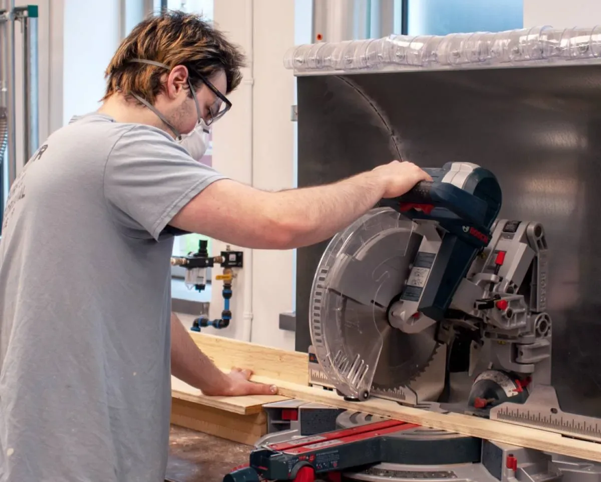 Étudiant qui manipule une machine à couper du bois