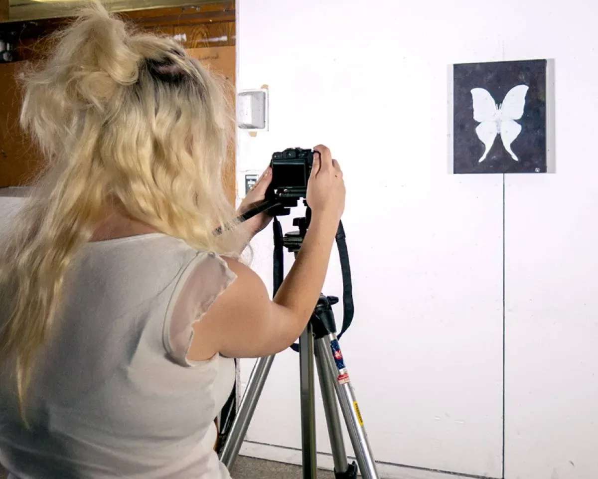 Étudiante qui prend une photo d'un tableau avec un papillon