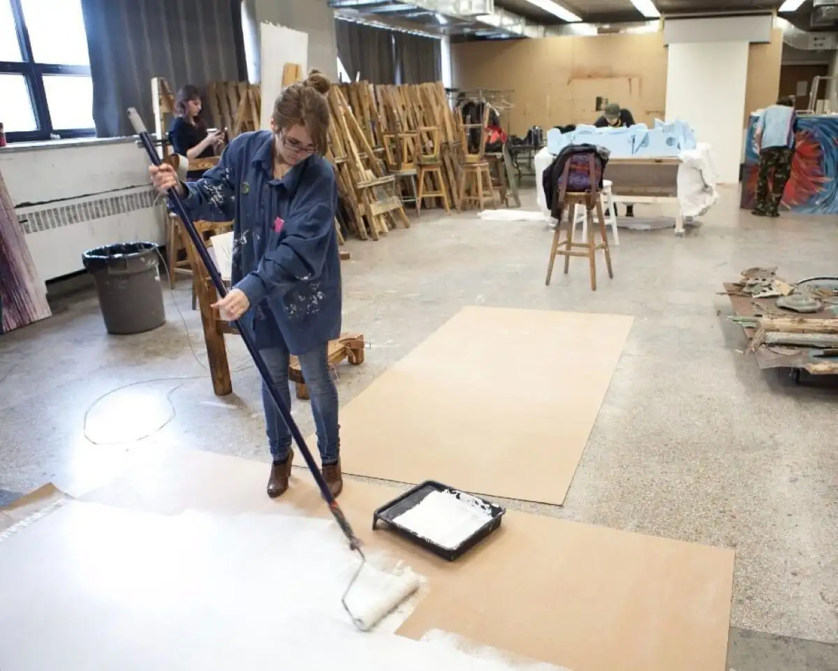 Étudiante qui peint une plaque au sol