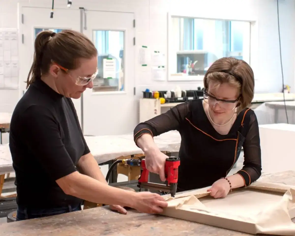 Étudiante qui travaille sur du bois supervisée par sa professeure
