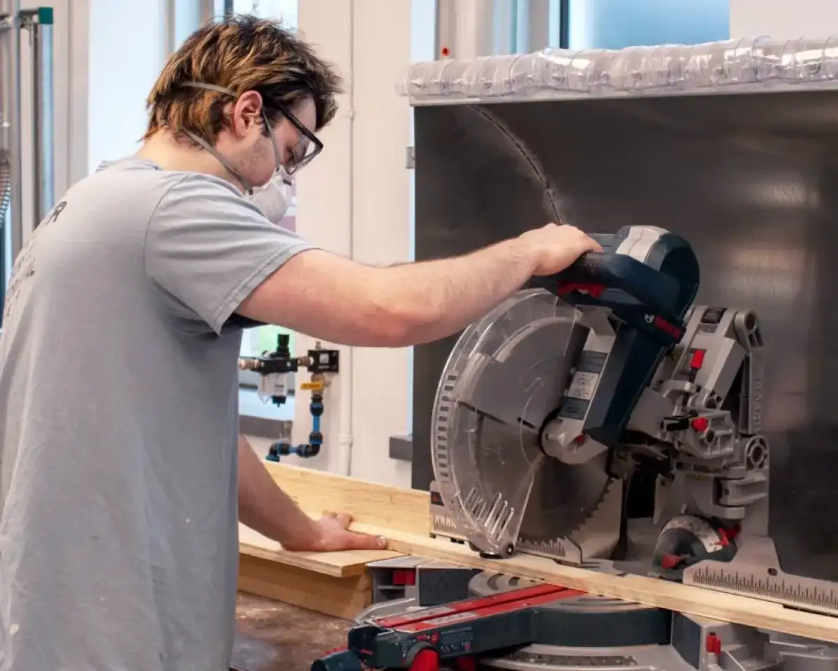 Étudiant qui manipule une machine à couper du bois