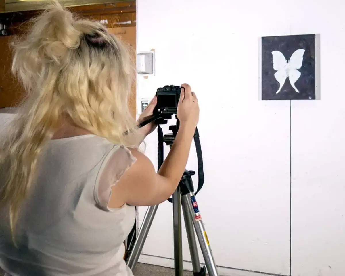 Étudiante qui prend une photo d'un tableau avec un papillon