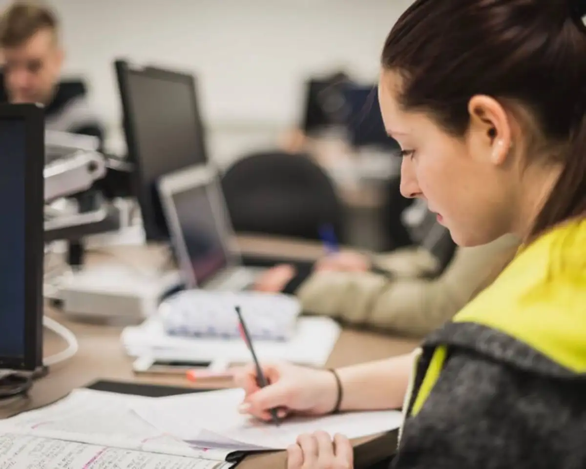 Étudiante qui prend des notes devant un ordinateur