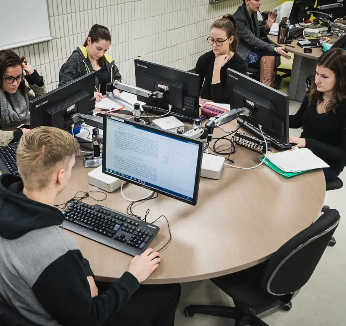 Personnes étudiantes dans une salle de classe autour d'ordinateurs
