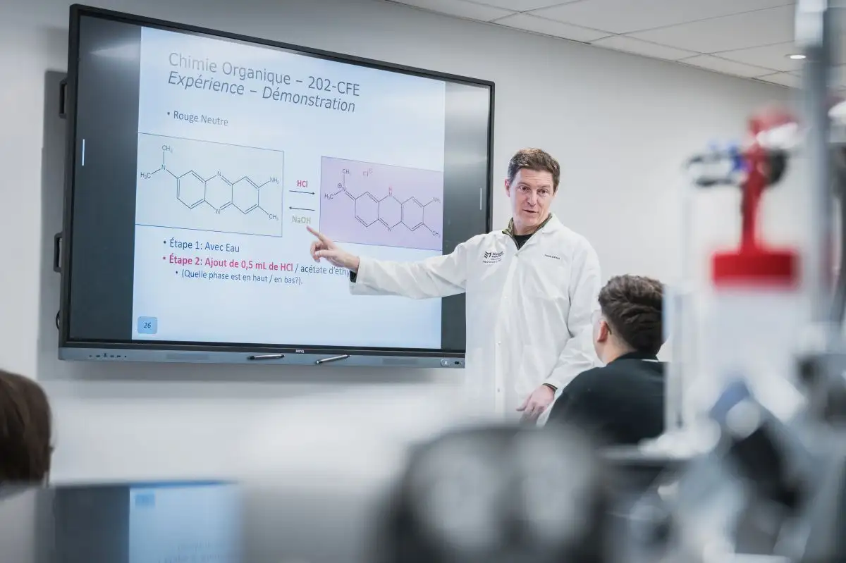 Enseignant de chimie pendant le cours qui pointe le téléviseur interactif