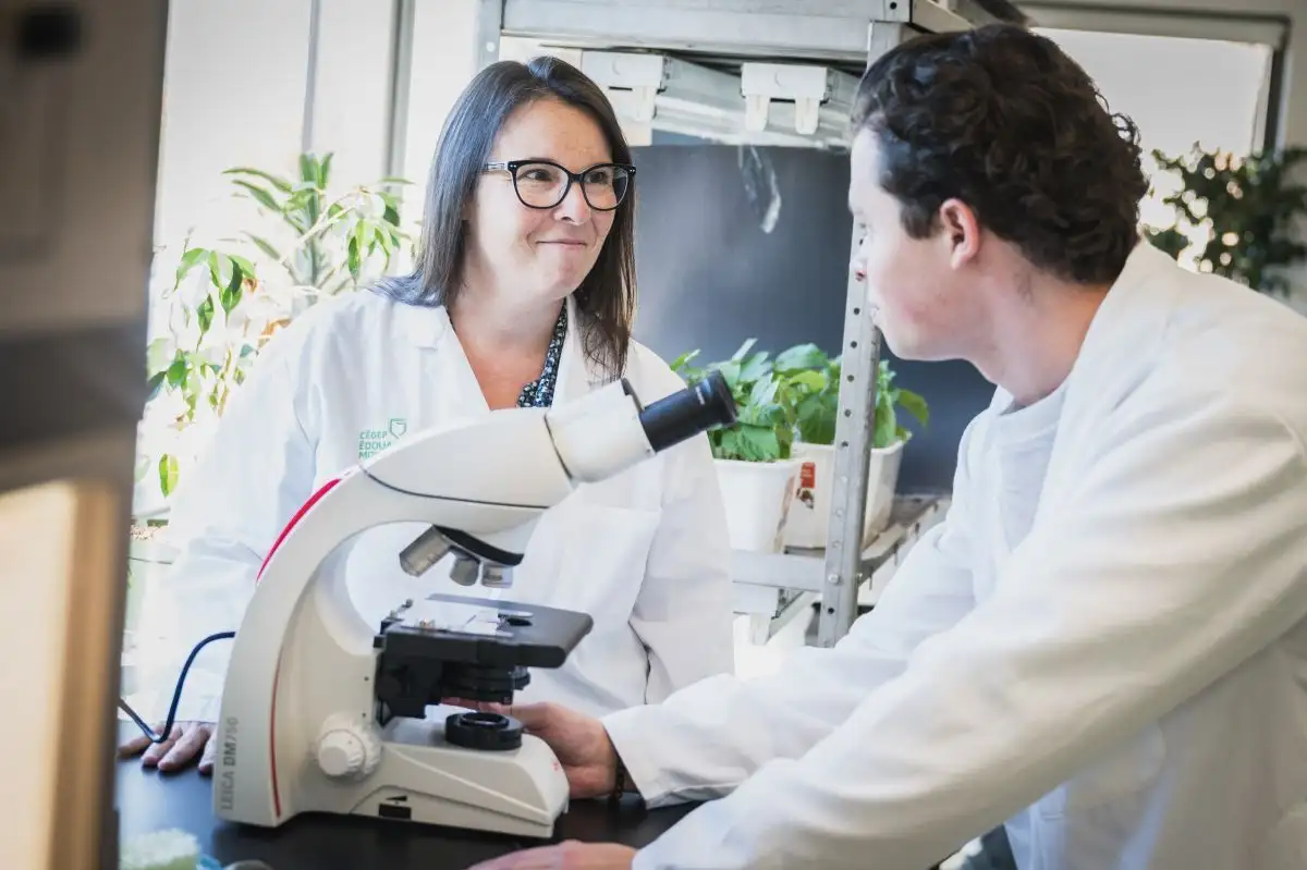 Enseignante et personne étudiante autour d'un microscope