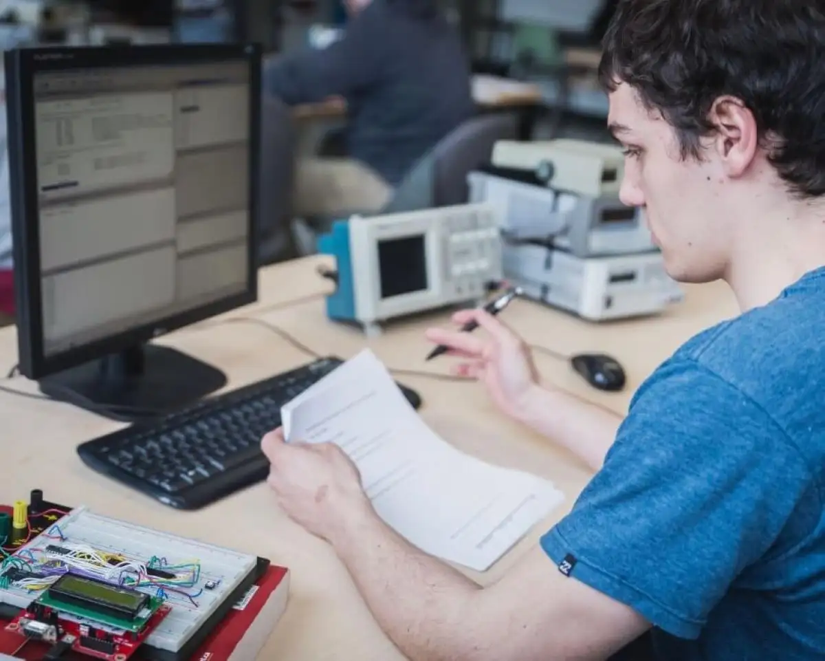 Étudiants qui vérifie des données sur une feuille en face d'un ordinateur
