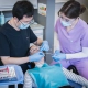 Personne enseignante et étudiante autour d'un patient en hygiène dentaire.