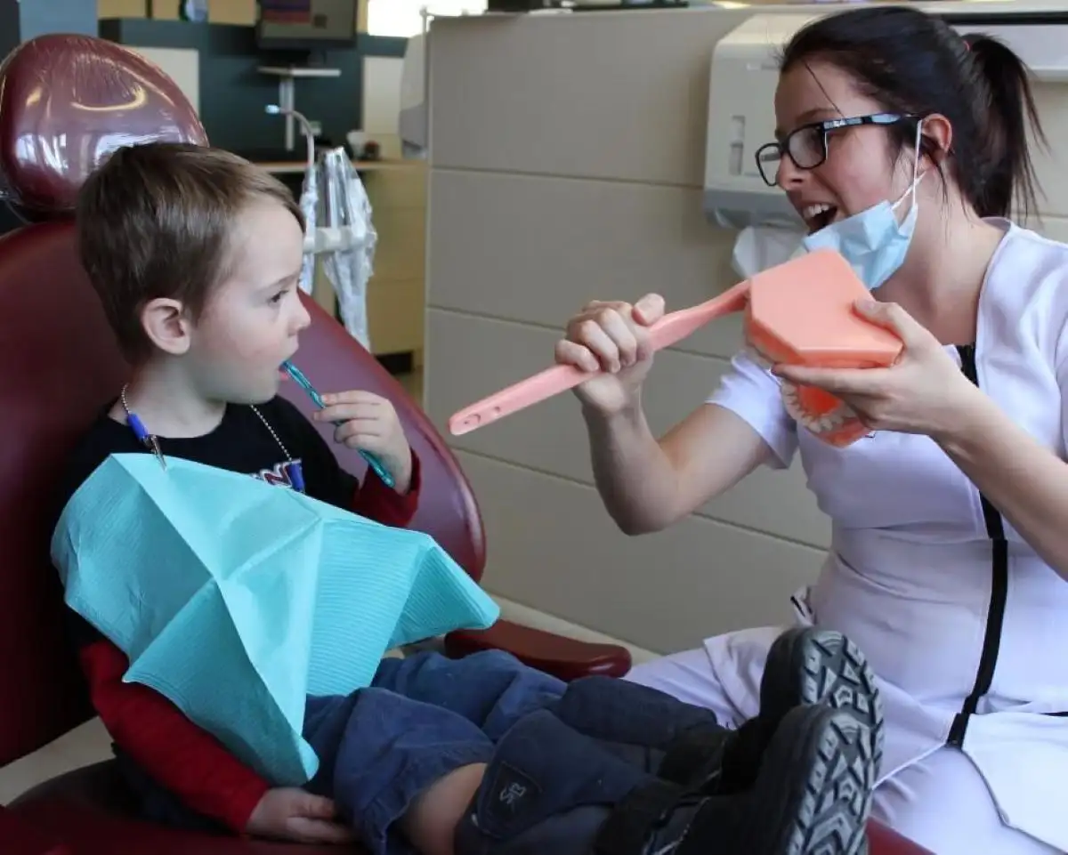 Étudiante qui montre à un enfant comment se brosser les dents