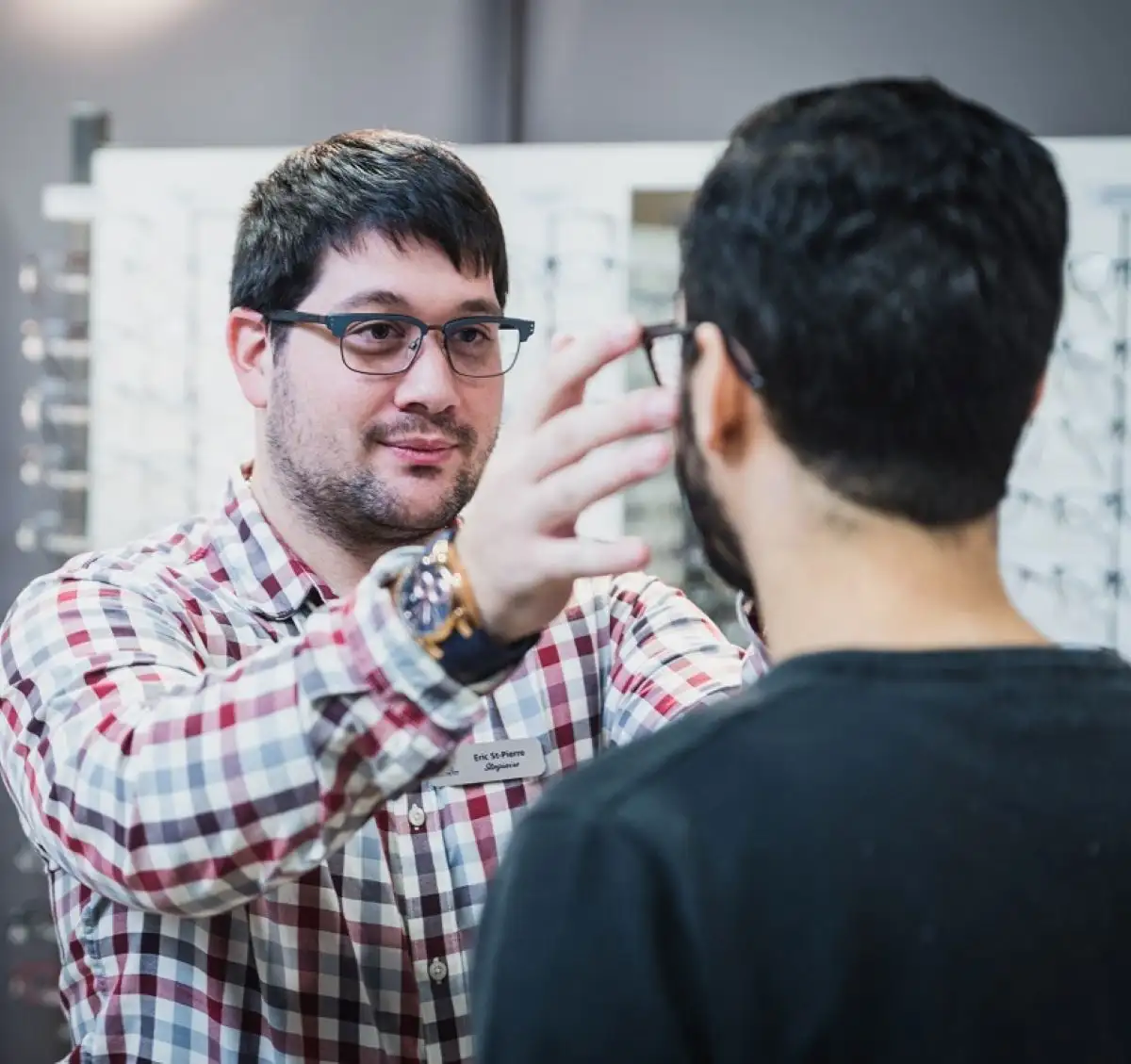 Étudiant qui aide un client à essayer une paire de lunettes