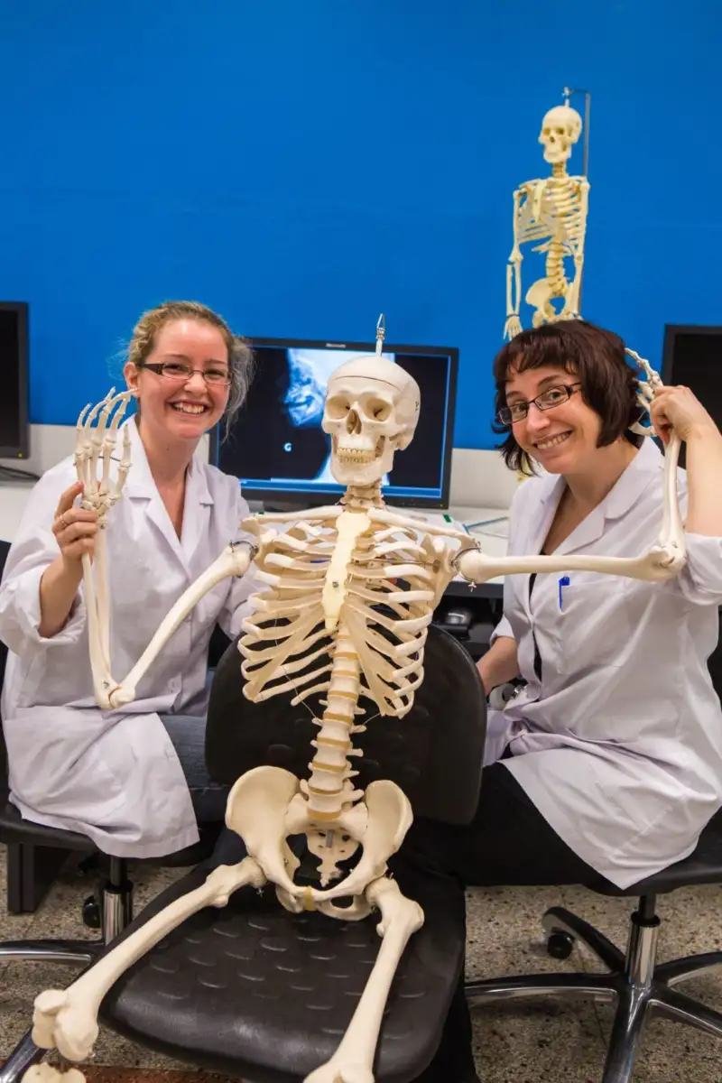 Deux étudiantes qui sourient avec un squelette sur une chaise