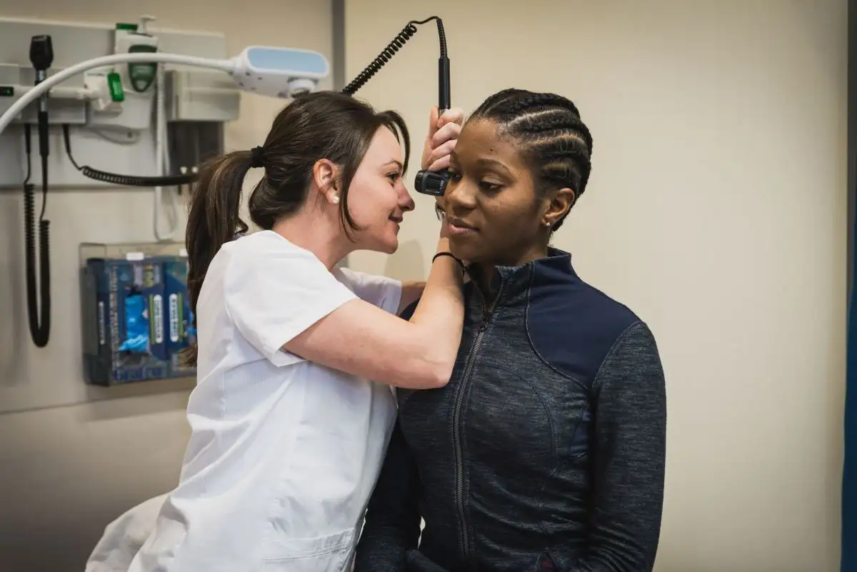 Étudiante qui ausculter l'oreille d'une patiente