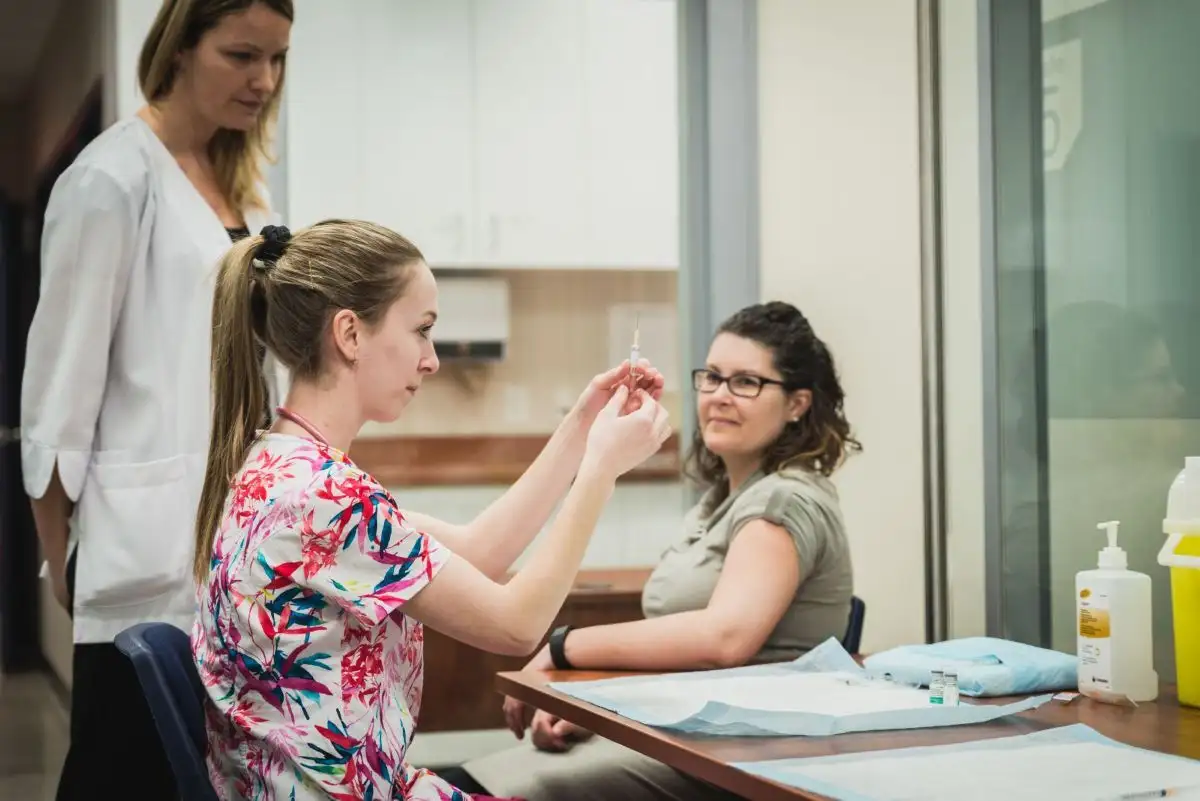 Étudiante qui manipule une seringue supervisée par sa professeure