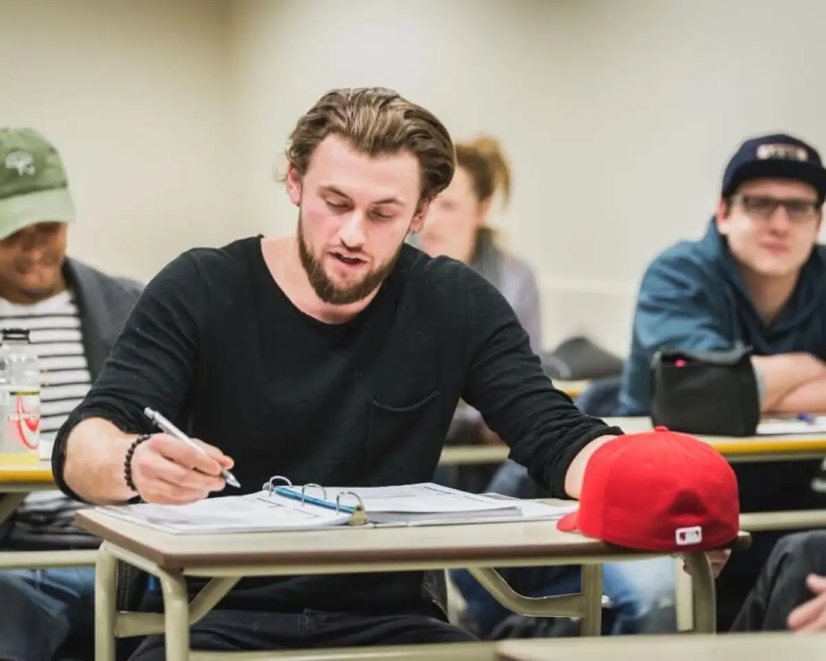 Focus sur un étudiant qui prend des notes dans une classe