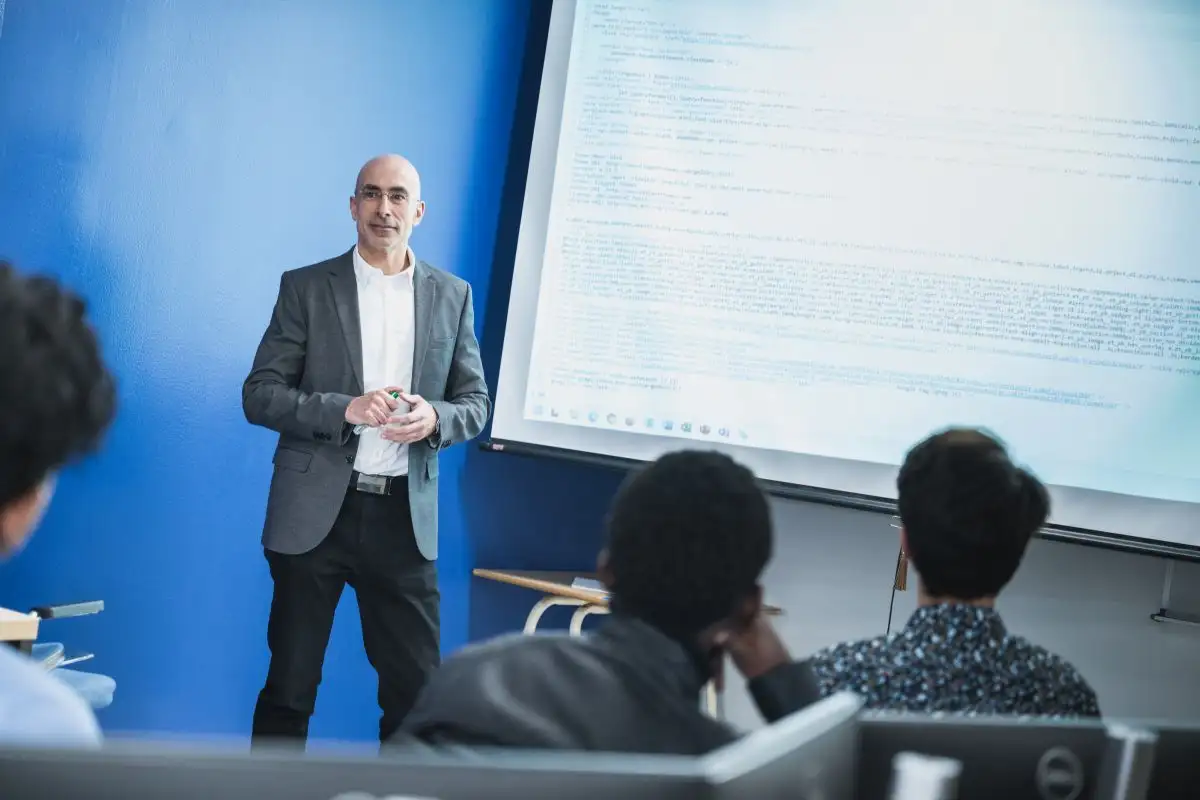 Enseignant devant un écran qui parle à sa classe