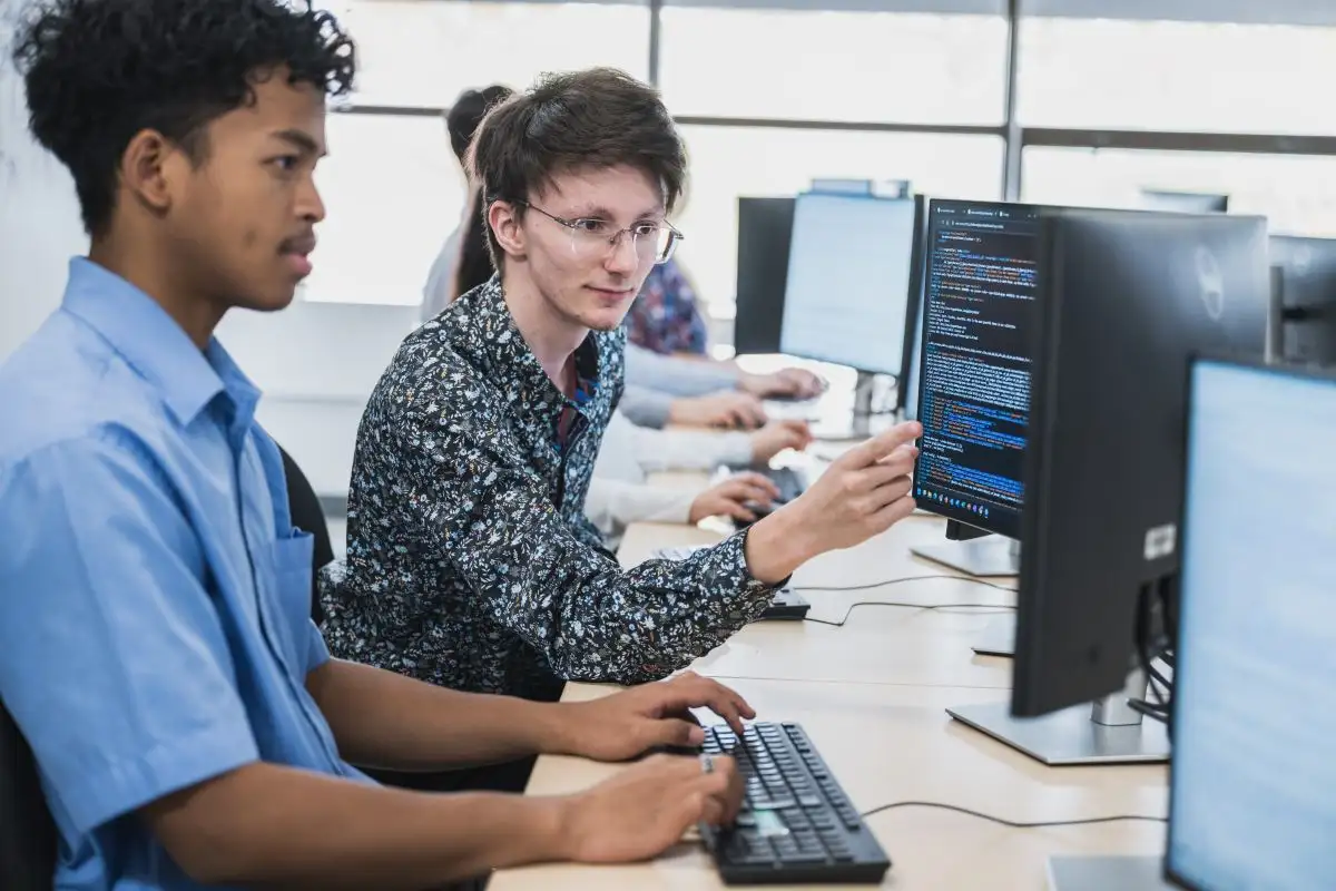 Personnes étudiantes qui discutent en face de leurs ordinateurs