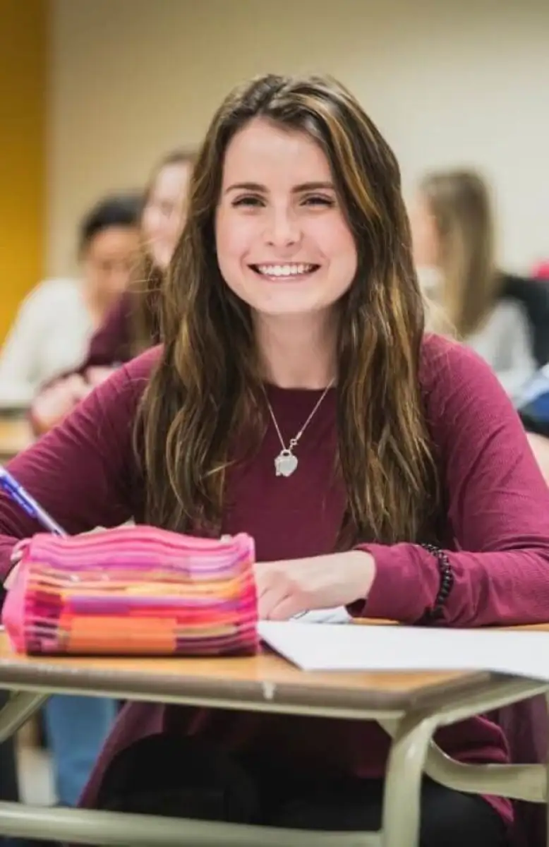 Personne étudiante a son bureau qui souris face caméra