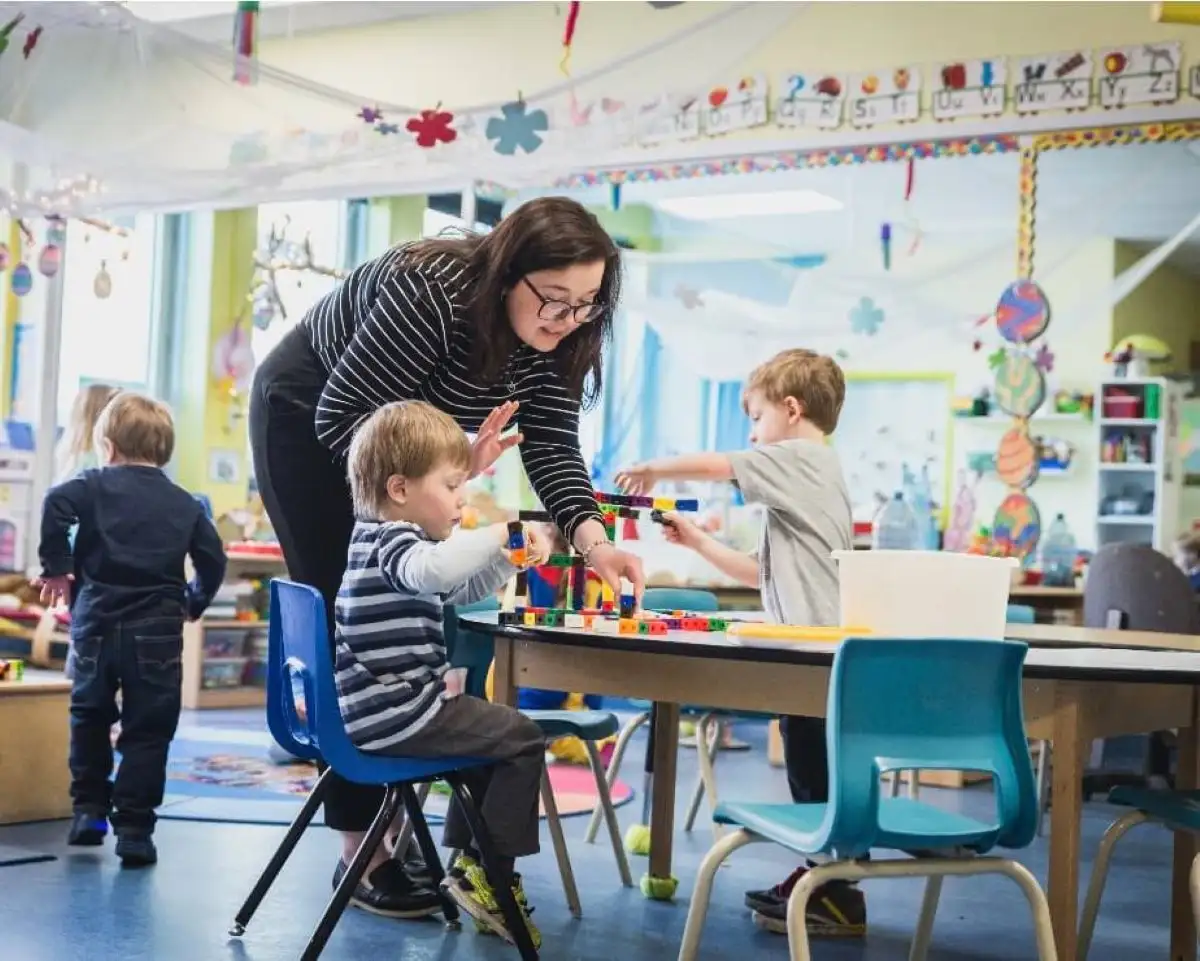 Éducatrice qui interagit avec les enfants à table