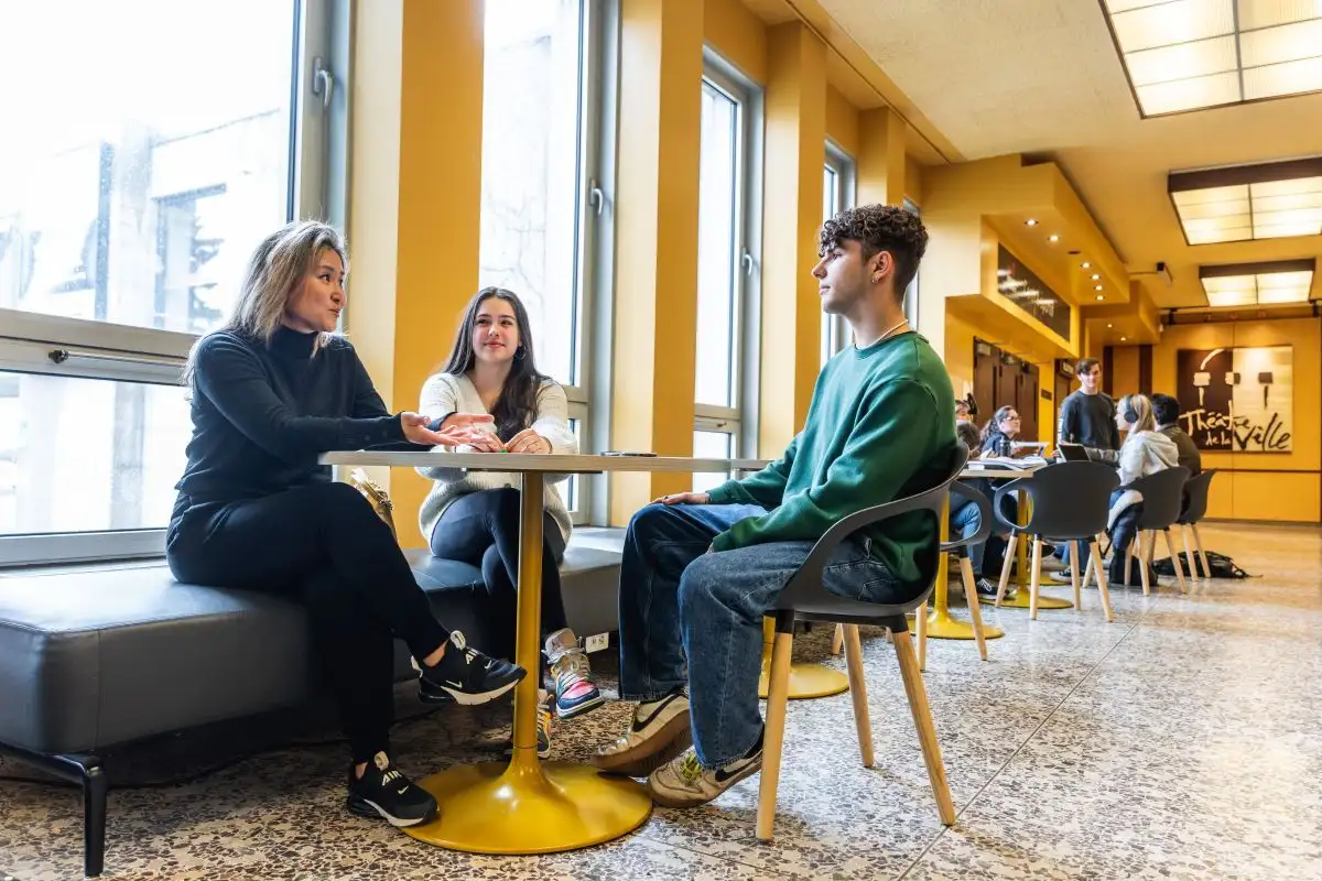 Personnes étudiantes qui discutent assises proche de l'entrée Le Caron