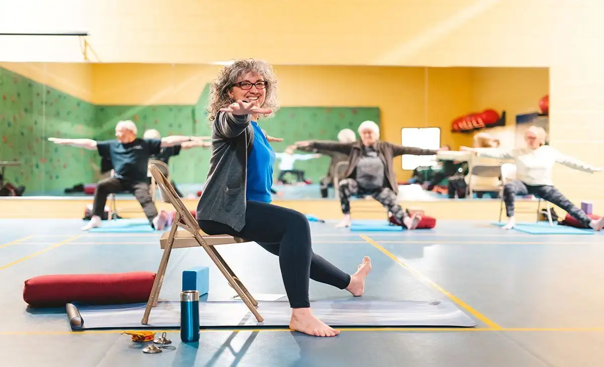 On voit des gens qui font des entraînements d'équilibre sur chaise dans une salle du Centre sportif